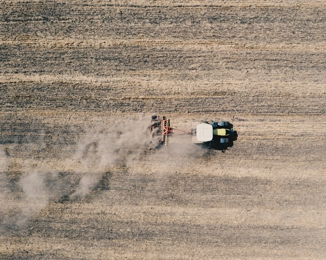 A tractor working a large dry field